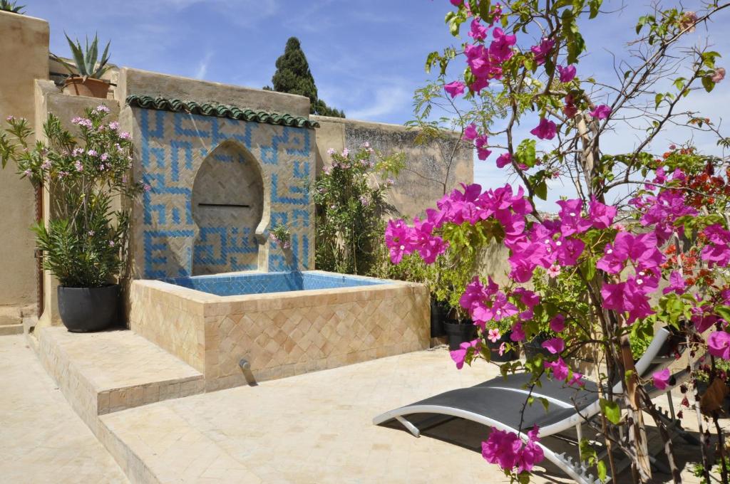 a garden with a fountain with purple flowers at Dar 7 Louyat in Fez