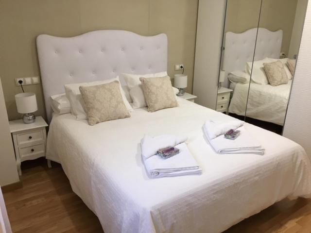 a bedroom with a white bed with two towels on it at Alojamiento La Rosaleda in Ponferrada