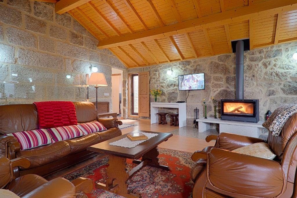 a living room with leather furniture and a fireplace at Casa da Macheta in Castro Laboreiro