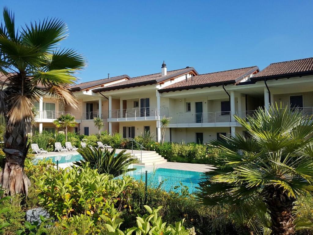 a resort with a swimming pool and palm trees at Luxury Apartments Beauty Gardens in Sirmione