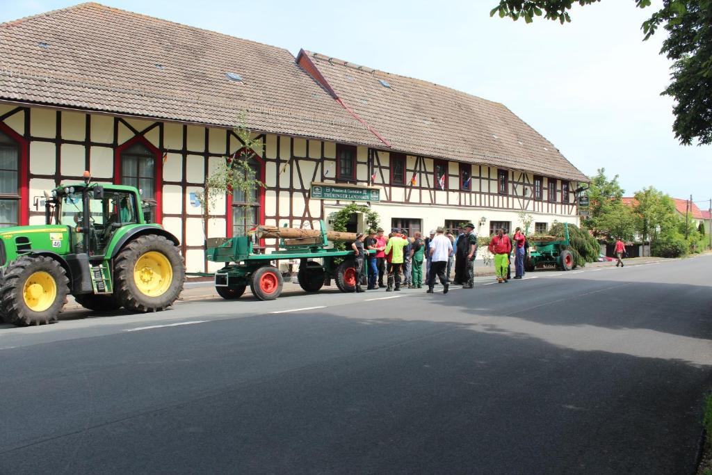 a group of people standing outside of a building with a tractor at Thüringer Landhaus in Allmenhausen