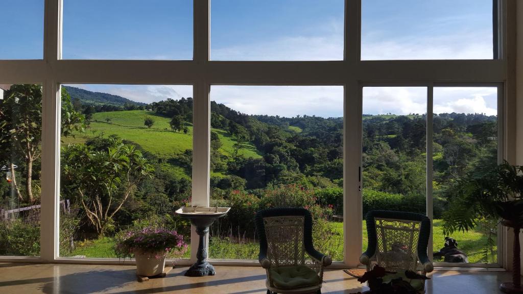 een groot raam met uitzicht op een groen veld bij Quinta Esencia in Alajuela