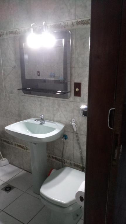 ein Badezimmer mit einem Waschbecken, einem WC und einem Spiegel in der Unterkunft Apartamento de hospedagem-calendula in Joinville