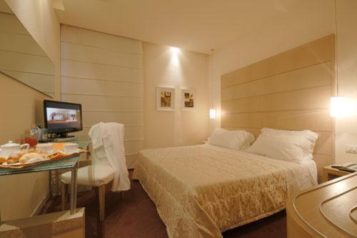 Schlafzimmer mit einem Bett und einem Schreibtisch mit einem TV in der Unterkunft Hotel First in Calenzano