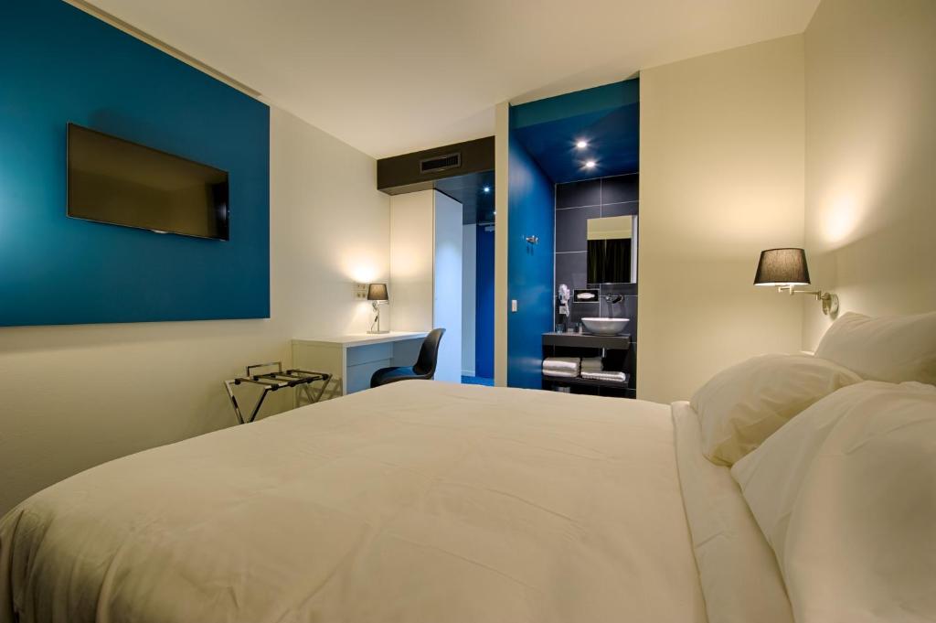 una camera con un letto bianco e una parete blu di Nex Hôtel a Tarbes