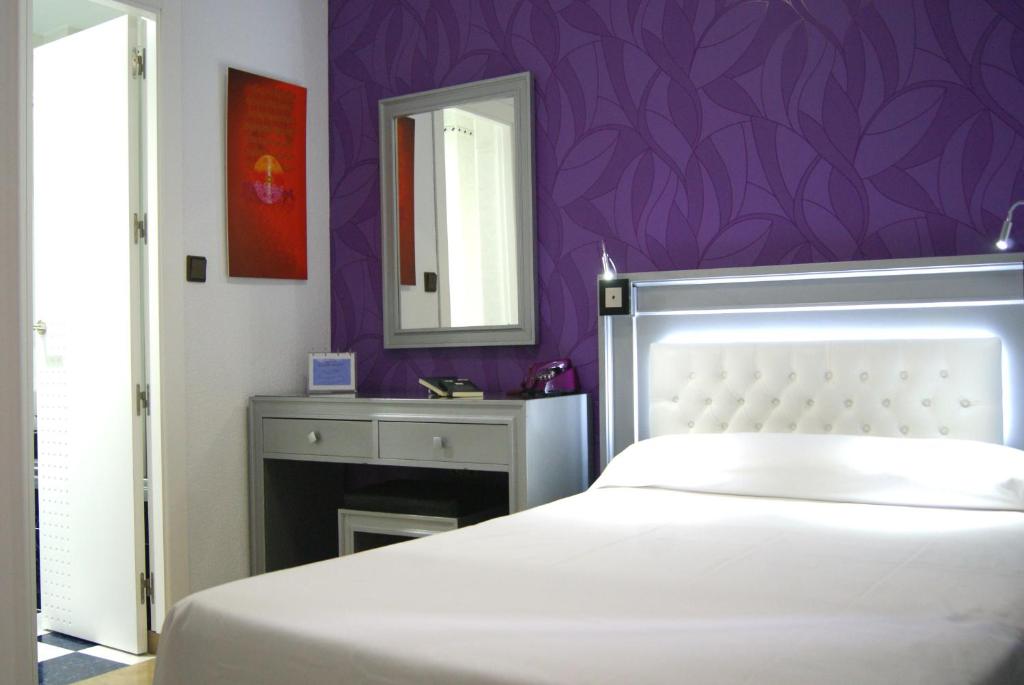 a bedroom with a white bed and a purple wall at Hotel Molinos in Granada