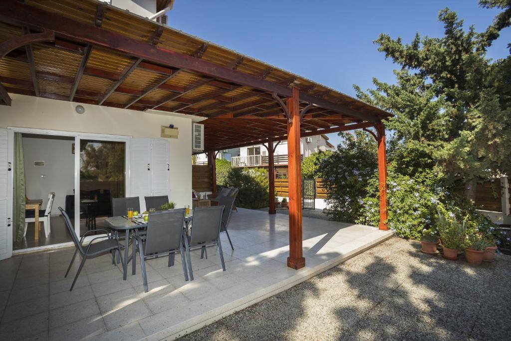 eine Terrasse mit einer hölzernen Pergola sowie einem Tisch und Stühlen in der Unterkunft Larnaca Villa Marina in Meneou