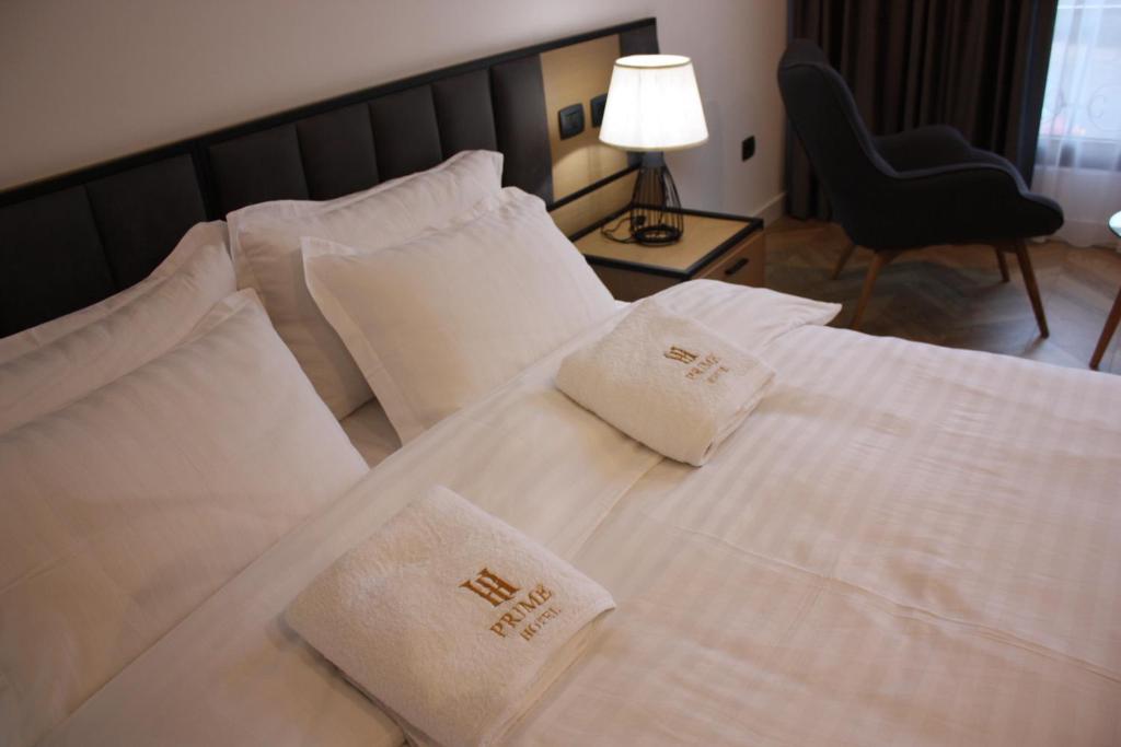 a hotel room with a bed with white sheets and pillows at Prime Hotel in Tirana