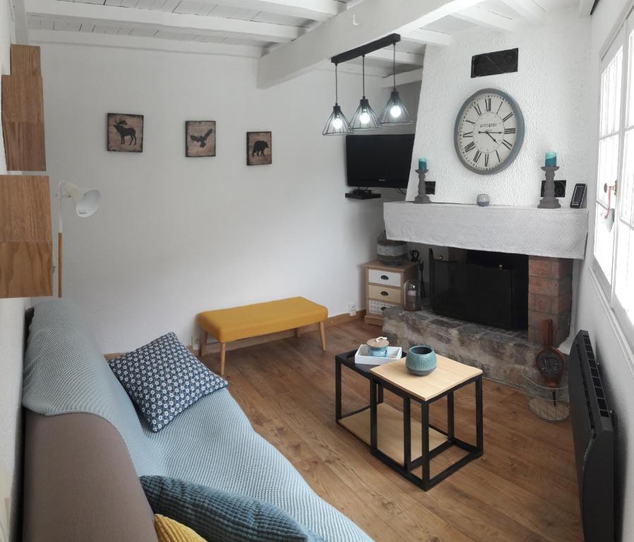 sala de estar con sofá y reloj en la pared en La Belle Audoise, en Sainte-Colombe-sur-Guette