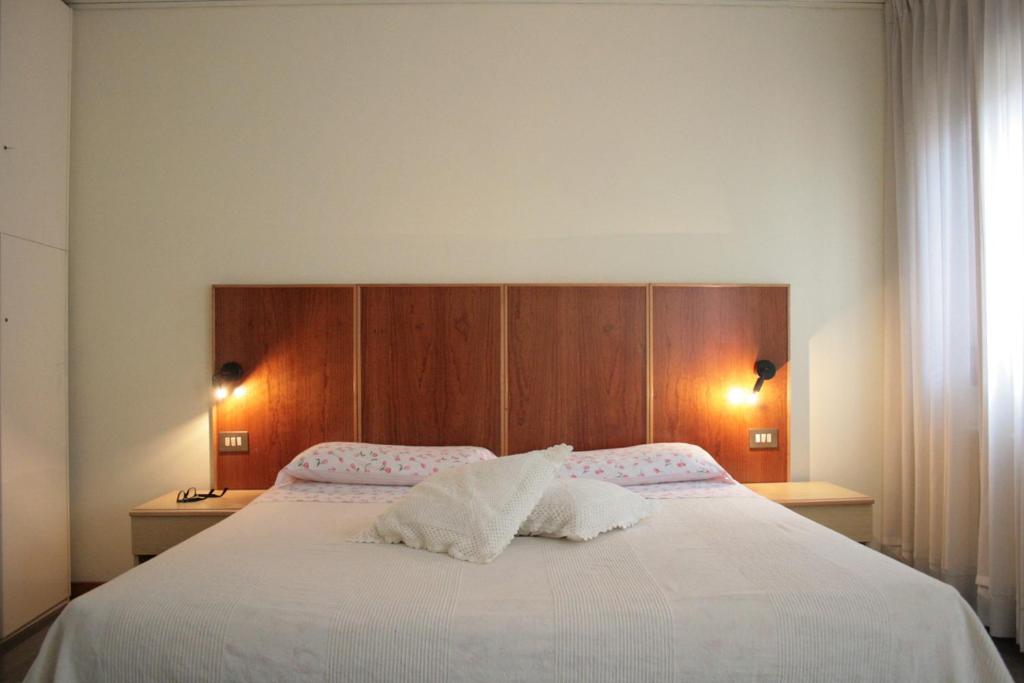 a bedroom with a large white bed with a wooden headboard at Bocca di Piazza in Venice