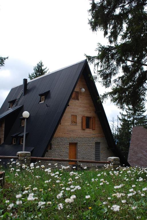 a house with a black roof and a field of flowers at Apartments A Vlasic in Vlasic