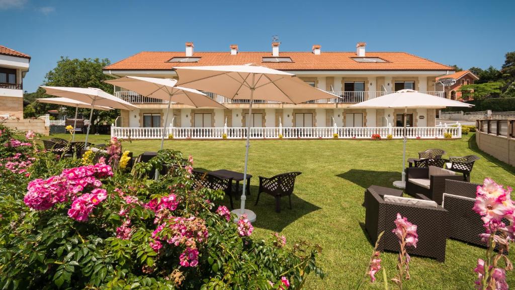 een huis met tafels en parasols in een tuin bij Hotel La Bolera in Isla