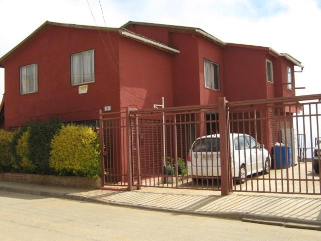 una casa roja con una puerta y un coche aparcado delante en Hospedaje Maria Teresa, en Valparaíso
