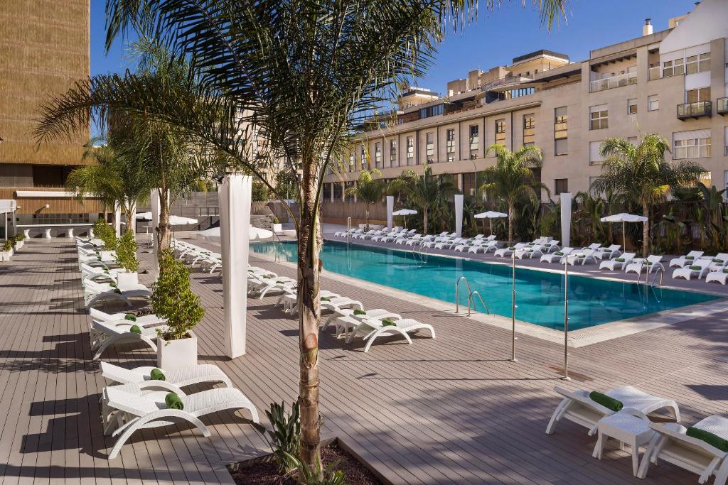 a beach with tables, chairs and umbrellas at Melia Lebreros in Seville