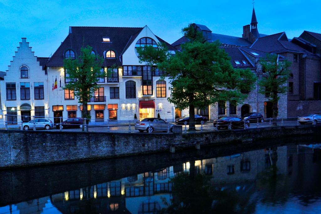 un groupe de bâtiments à côté d'une rivière dans l'établissement Golden Tulip Hotel de’ Medici, à Bruges
