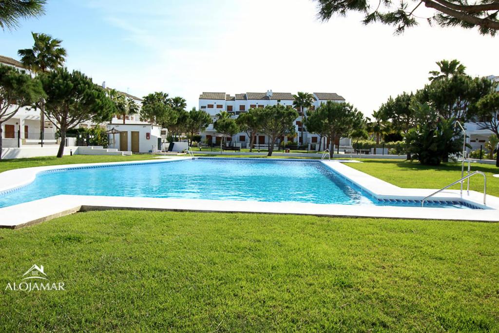 - une piscine dans une cour avec des arbres et des maisons dans l'établissement Residencial Carrajolilla, à Chiclana de la Frontera
