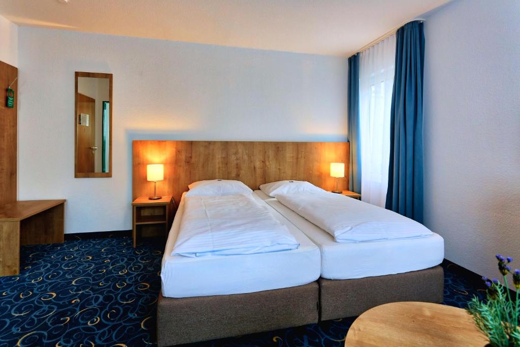a hotel room with two beds and a mirror at Appartis - Hotel am Stadtpark in Sindelfingen