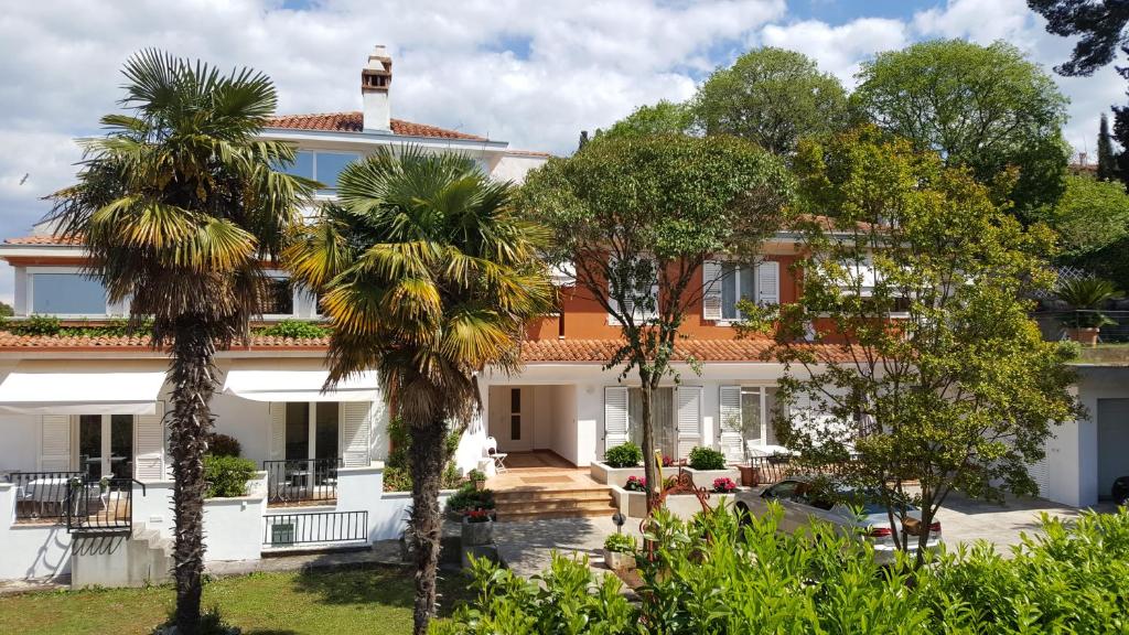 a large white house with palm trees in front of it at Corte dei merli Apartment & Studio in Rovinj