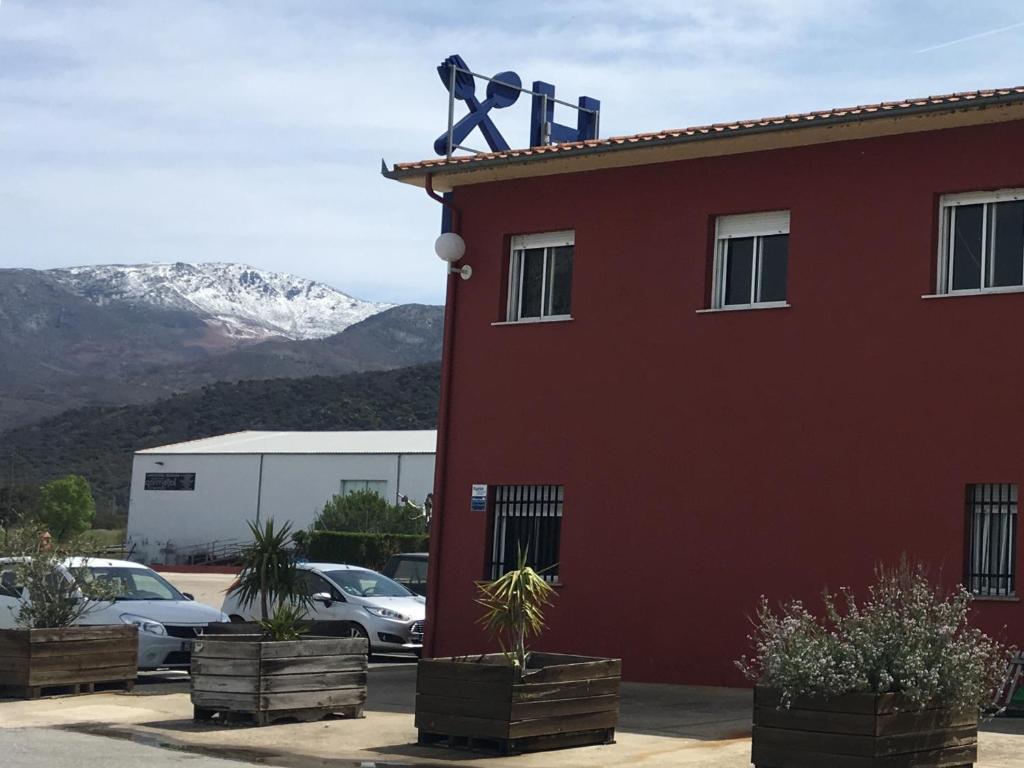 ein rotes Gebäude mit einem schneebedeckten Berg im Hintergrund in der Unterkunft Hostal Asturias in Jarilla