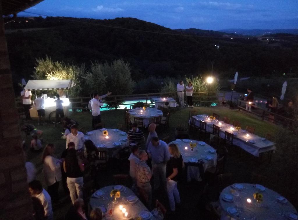 grupa ludzi stojących przy stołach w nocy w obiekcie Agriturismo San Fedele w mieście Perugia