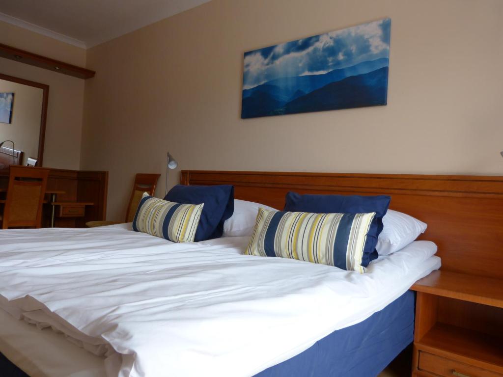 a bedroom with a large white bed with blue pillows at Apartament Grażyna in Krynica Zdrój