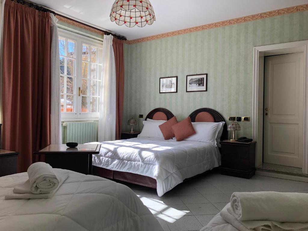 a bedroom with two beds and a chandelier at Albergo Sapori in Tolè