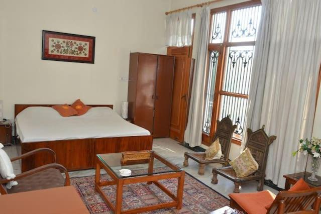 1 dormitorio con cama, sillas y mesa en Sandy's Homestay, en Jammu