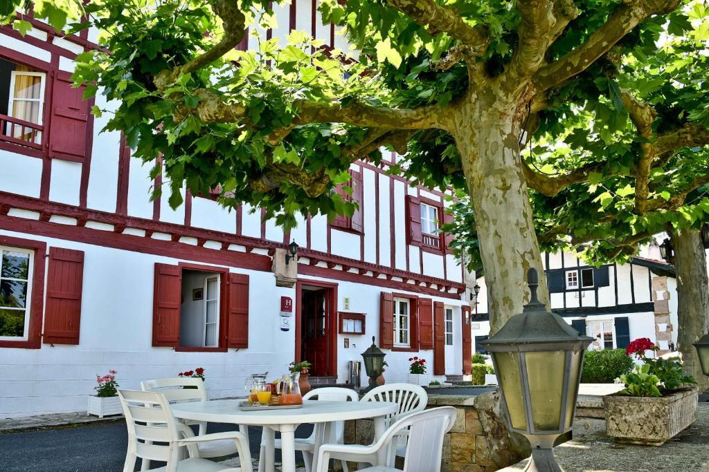 una mesa y sillas bajo un árbol frente a un edificio en Logis Hôtel Baratxartea, en Sare