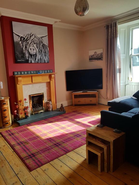 a living room with a fireplace and a flat screen tv at The Herring Queen in Eyemouth