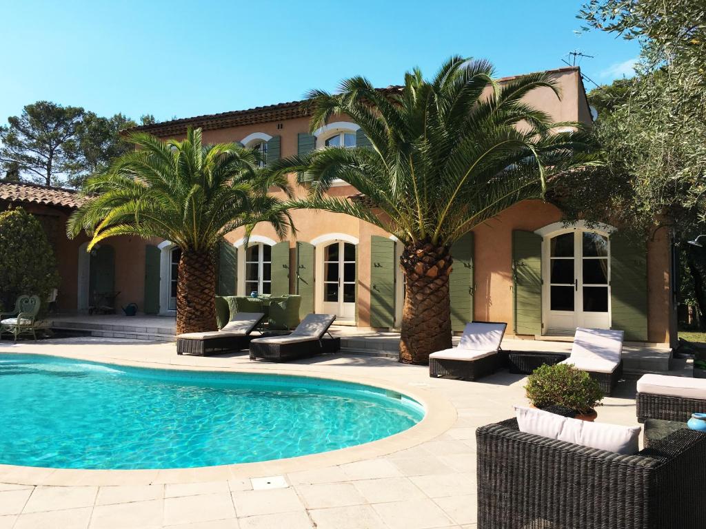 a swimming pool in front of a house with palm trees at Le Champmazet in La Roquette-sur-Siagne