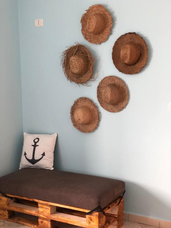 um quarto com um banco e alguns chapéus de palha na parede em Casa Natali em Durrës