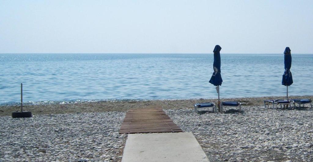 two umbrellas and chairs on a beach with the ocean at Yialos Luxury Apartments in Perivolia