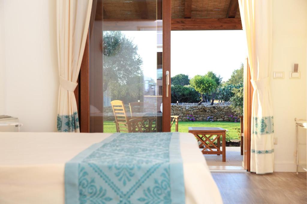 a bedroom with a bed and a view of a yard at Inghirios Wellness Country Resort in Santa Maria la Palma