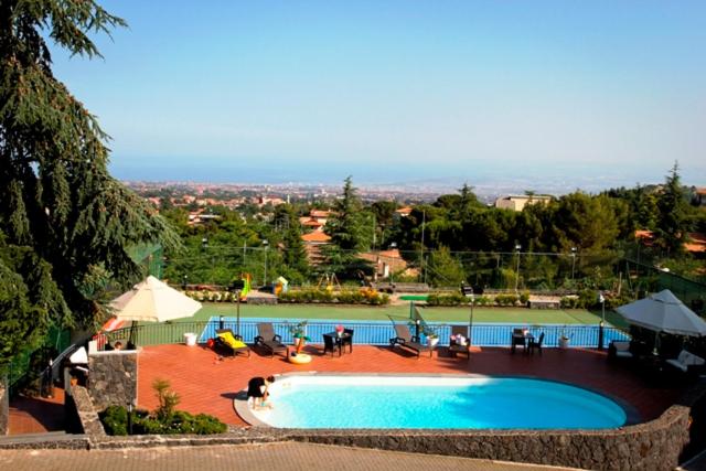 a swimming pool with chairs and umbrellas next to at Etna Hut in Nicolosi
