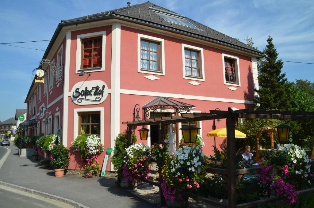 ein rosafarbenes Gebäude mit Blumen davor in der Unterkunft Gasthof Safenhof in Bad Waltersdorf
