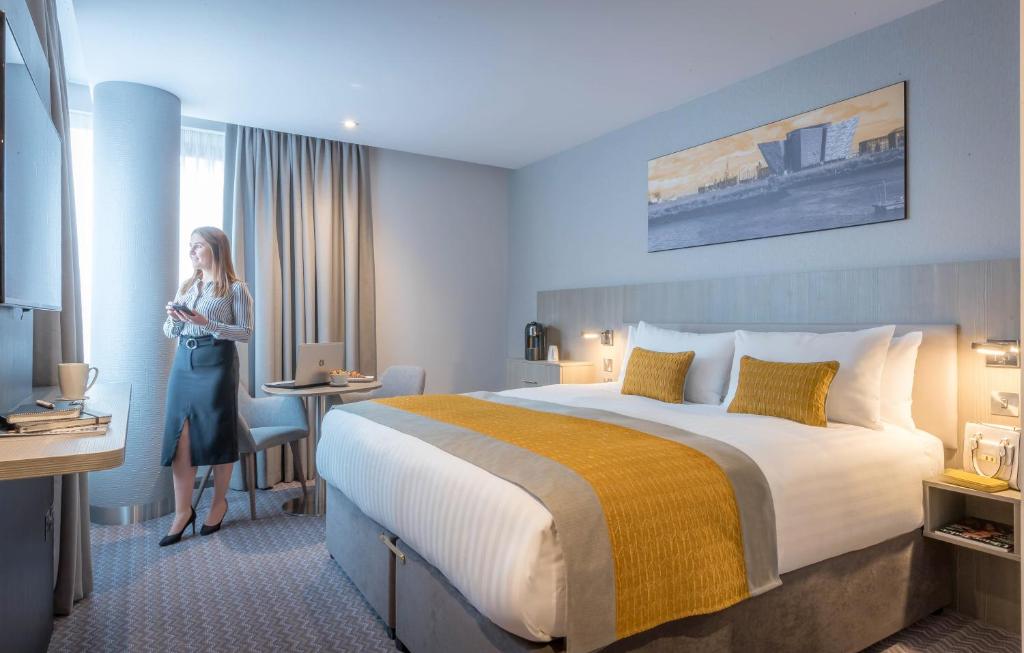 a woman standing in a hotel room with a bed at Maldron Hotel Kevin Street, Dublin City in Dublin