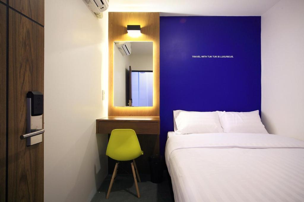um quarto com uma cama, um espelho e uma cadeira em Tuk Tuk Hostel em Bangkok