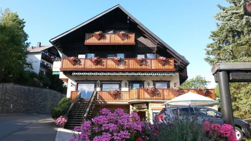 uma casa com uma varanda com flores em frente em Pension Göbel em Willingen