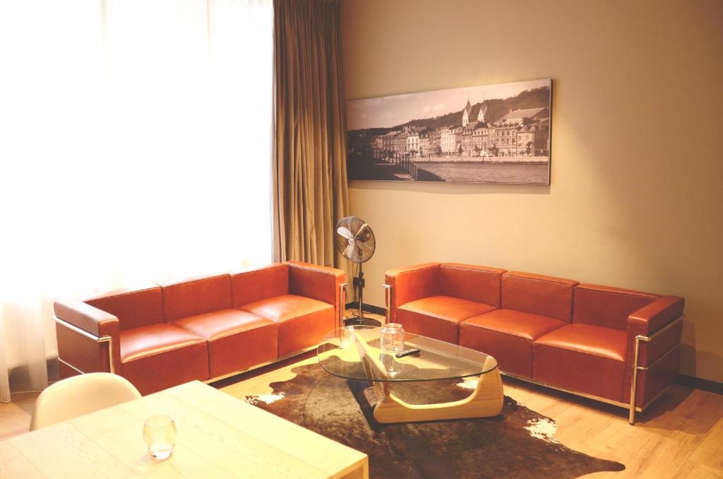 a living room with two leather couches and a table at Amosa Liège City Centre Apart Donceel 6 in Liège