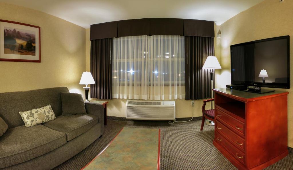 a living room with a couch and a flat screen tv at Days Inn & Suites by Wyndham Langley in Langley