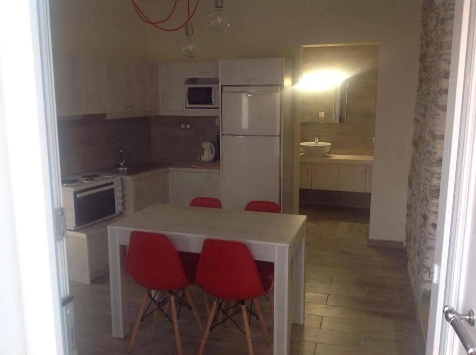 a kitchen with a white table and red chairs at George Home 1 in Balíon