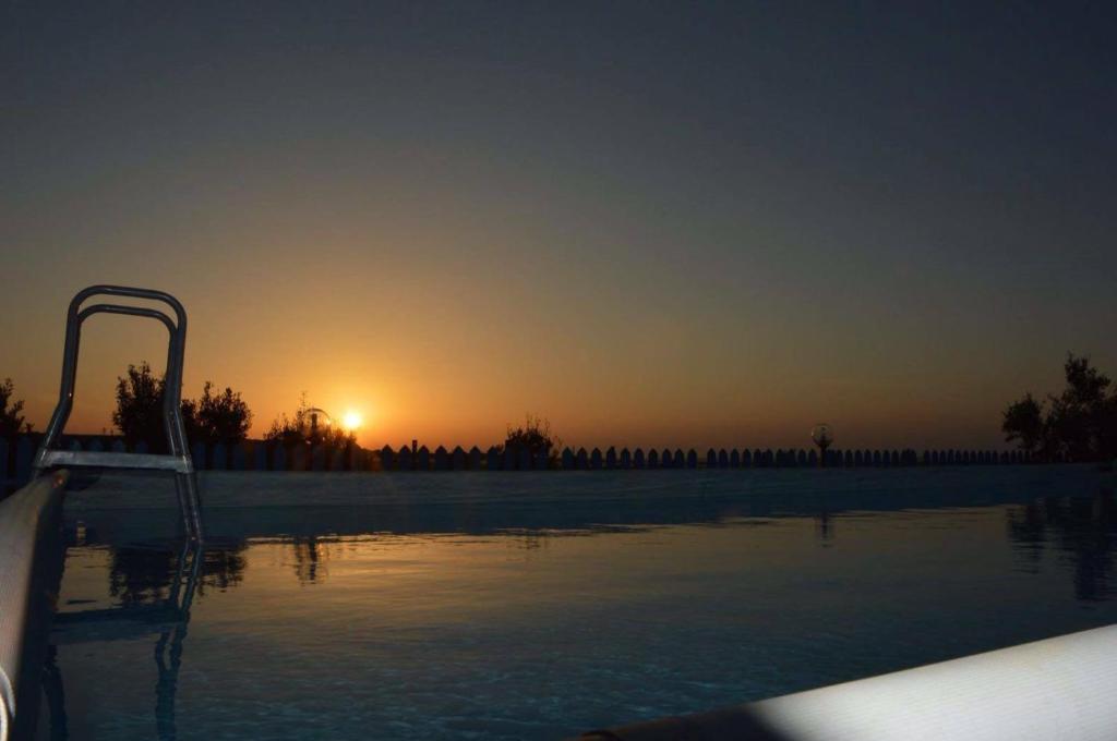 a swimming pool with the sunset in the background at Baglio Del Sole in San Vito lo Capo