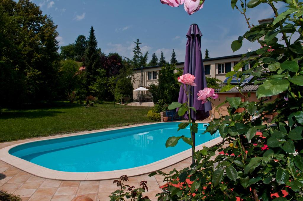 a swimming pool in a yard with an umbrella and flowers at Landhaus Hindenburg in Bad Gleichenberg
