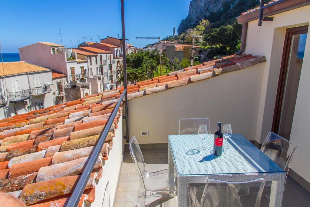 een tafel met een fles wijn op een balkon bij Terrazza di Svevia in Cefalù