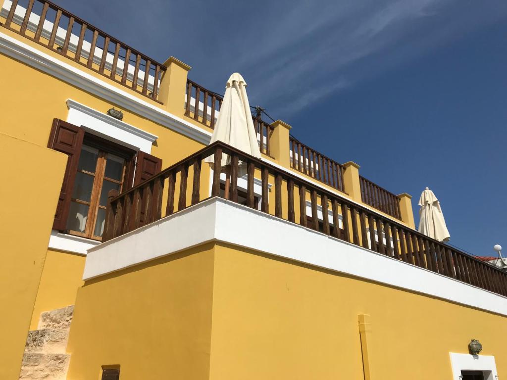 un edificio amarillo con un balcón con sombrillas. en Villa Amalia, en Halki