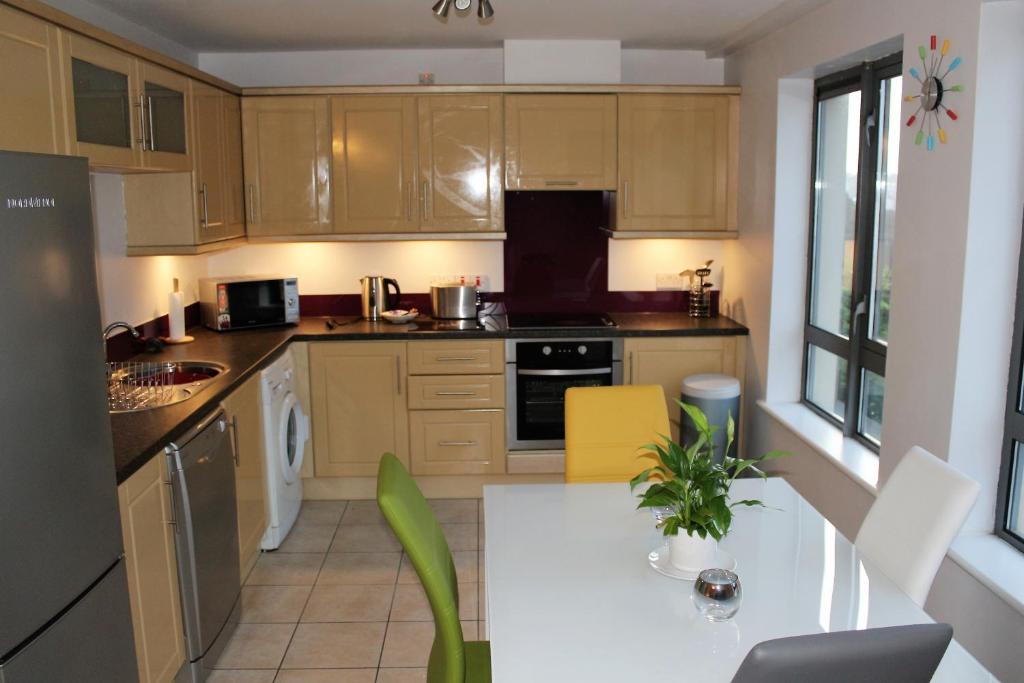 uma cozinha com armários de madeira e uma mesa branca em Wild Atlantic Accommodation 18 Glenveagh Court em Letterkenny