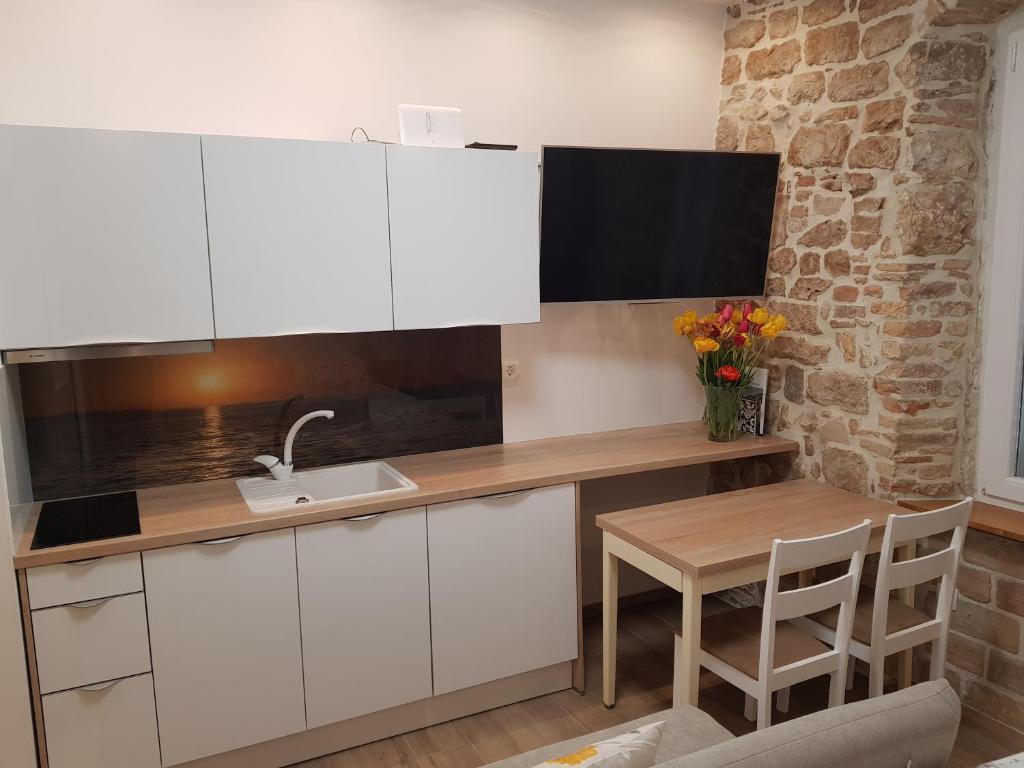 a kitchen with white cabinets and a sink and a table at Studio Apartment B&B Zadar Sunset in Zadar