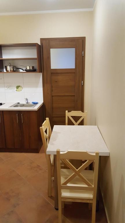 ミコワイキにあるApartament Słoneczna 3のドア付きキッチン(テーブル、椅子付)