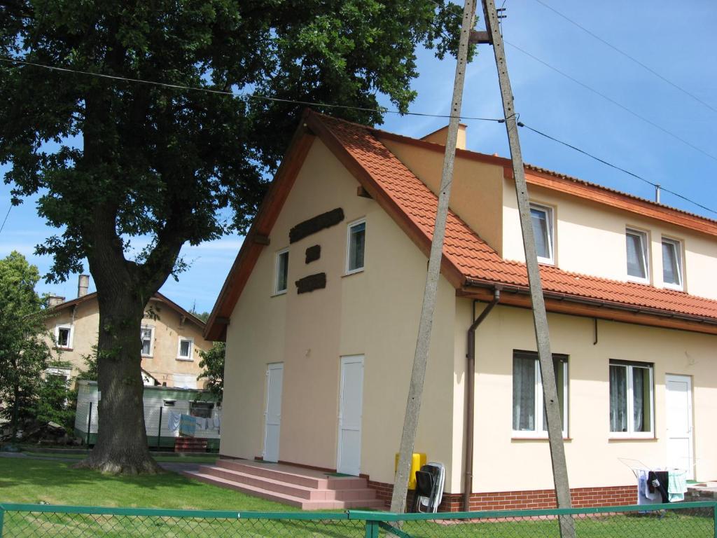 dom z drzewem przed nim w obiekcie Apartamenty pod dębem w Łukęcinie