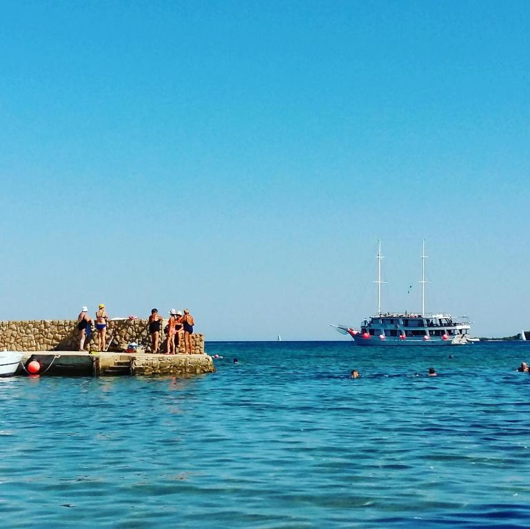 um grupo de pessoas em pé em um cais com um barco em Melada em Molat